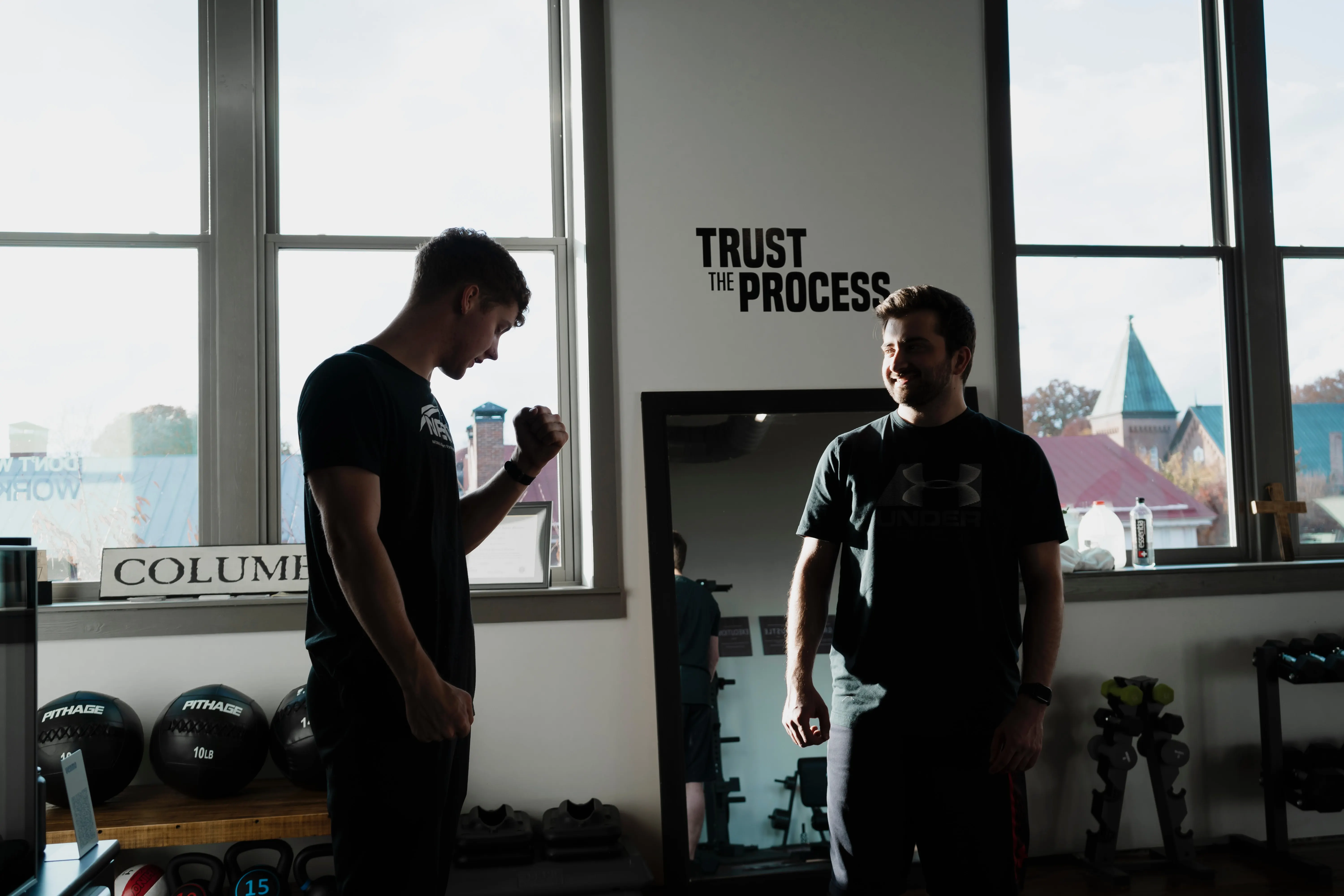 Two men at gym on is a personal trainer.